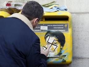 French street artist Christian Guemy, known as C215, cleans the vandalized mailboxes with swastikas covering the face of the late Holocaust survivor and renowned French politician, Simone Veil, in Paris, Tuesday Feb.12, 2019. According to French authorities, the total of registered anti-Semitic acts rose to 541 in 2018 from 311 in 2017, a rise of 74 percent.