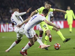 Lyon defender Marcelo, left, and Lyon defender Leo Dubois, center, challenge Barcelona defender Jordi Alba, right, during the Champions League round of 16 first leg soccer match between Lyon and FC Barcelona in Decines, near Lyon, central France, Tuesday, Feb. 19, 2019.