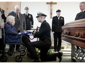 Rita Mendonsa, left, receives the flag that draped her husband George's casket during funeral services at St. Columba Cemetery in Middletown, R.I., Friday, Feb. 22, 2019. George Mendonsa, the sailor sailor photographed kissing a woman in Times Square in New York at the end of World War, died Sunday at age 95.