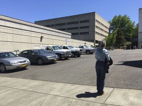 FILE - In this Wednesday, May 24, 2017 photo, Terry Carlisle looks at the Douglas County Jail in Roseburg, Ore., where she was incarcerated under what she describes as horrific conditions in 2015 for drunken driving. After being sued by a woman who was jailed under conditions she described as inhumane, officials in an Oregon county have agreed to lower the number of inmates crammed into a single cell, allow them showers twice a week and provide menstruating prisoners with hygiene products.