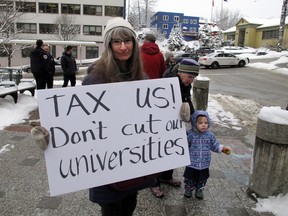Luann McVey holds a sign before the start of a rally held in support of the Alaska university system on Wednesday, Feb. 13, 2019, in Juneau, Alaska. McVey said she's worried about the impact of proposed cuts on the University of Alaska system. Gov. Mike Dunleavy's budget proposal includes deep cuts to public education, the university system, Medicaid and Alaska's ferry system. The budget plan also eliminates state support for public broadcasting and proposes changes in petroleum property tax collections that will benefit the state but affect areas like the North Slope Borough.
