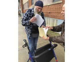 Ray Kemble, left, and Craig Stevens look through papers outside  the Susquehanna County Courthouse in Montrose, Pennsylvania, on Feb. 4, 2018. A gas driller backed off its demand to have Kemble, a Pennsylvania homeowner who's long accused the company of polluting his water, thrown in jail over his failure to submit to questioning as part of the company's $5 million lawsuit against him. (AP Photo/Michael Rubinkam)