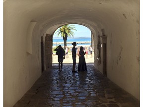In this June, 27, 2018 photo, tourists walk through a tunnel at the medieval-area Castle of Lagos in Lagos, Portugal. Lagos, a striking Portuguese beach town of charming coastlines and slightly sandstone cliffs, is the birthplace of the African slave trade in Europe. A museum dedicated to slavery is helping this enclave in the heart of southern Portugal's Algarve region come to terms with its history.