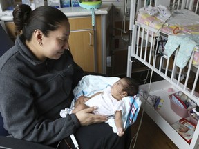 Theodora Flores holds one of her twin daughters, Genesis, in a patient room at the Ann & Robert H. Lurie Children's Hospital of Chicago on Wednesday, Feb. 27, 2019. Genesis is wearing wireless sensors developed by researchers at Northwestern University to monitor newborns without hurting their skin or blocking parents' cuddles.