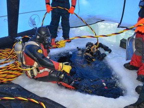 RCMP members enter Peter Pond Lake in Saskatchewan through a hole cut in the ice in this undated image provided by the RCMP.