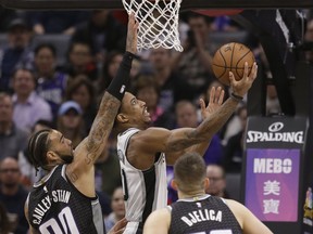San Antonio Spurs guard DeMar DeRozan, center, goes to the basket against Sacramento Kings' Willie Cauley-Stein, left, and Nemanja Bjelica, right, during the first quarter of an NBA basketball game Monday, Feb. 4, 2019, in Sacramento, Calif.