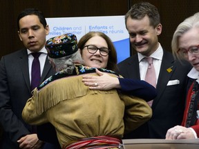 Metis National Council Clement Chartier hugs Jane Philpott, President of the Treasury Board and Minister of Digital Government, during a press conference regarding the introduction of Bill C-92, An Act respecting First Nations, Inuit and Métis children, youth and families in Ottawa on Thursday, Feb. 28, 2019. Indigenous Services Minister, Seamus O'Regan, back right, and Natan Obed, president of Inuit Tapiriit Kanatami, look on.