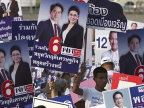 Supporters raise posters of candidates of Pheu Thai Party during an election campaign in Bangkok, Thailand, Friday, Feb. 15, 2019. The nation's first general election since the military seized power in a 2014 coup is expected to be held on March 24.