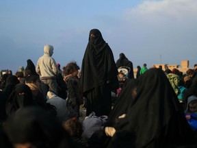 Women and children who fled the Islamic State (IS) group's last embattled holdout of Baghouz wait to be searched by US-backed Syrian Democratic Forces (SDF) fighters (not pictured) in Syria's northern Deir Ezzor province, on February 22, 2019.