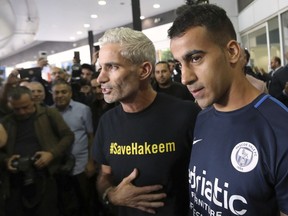 Refugee soccer player Hakeem Al-Araibi, right, arrives in Melbourne, Australia, Tuesday, Feb. 12, 2019, flanked by former Australia national team captain Craig Foster. Al-Araibi returned to Australia after the threat of extradition to Bahrain was lifted and three months after he was detained in Thailand.