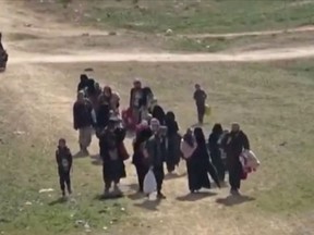 In this Sunday, Feb. 10, 2019 image from video provided by Hawar News Agency, ANHA, an online Kurdish news service, civilians flee fighting near Baghouz, Syria. Fierce fighting was underway Monday between U.S.-backed Syrian forces and the Islamic State group around the extremists' last foothold in eastern Syria. The capture of the IS-held village of Baghouz and nearby areas would mark the end of a four-year global war to end IS' territorial hold over large parts of Syria and Iraq, where the group established its self-proclaimed "caliphate" in 2014. (ANHA via AP)