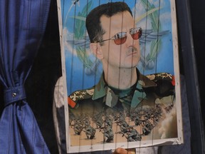 In this Aug. 13, 2018 file photo, a Syrian refugee holds a poster of President Bashar Assad in a bus window at the border crossing point of Jdedeh Yabous, on his way to Syria.