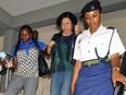 In this photo taken on Wednesday Oct. 7, 2015, Chinese national Young Feng Glan, centre, is escorted by police from Kisutu Resident's Magistrate Court in Dar es Salaam, Tanzania.