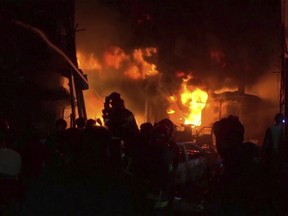 In this image made from a video, firefighters try to extinguish flames at buildings in Dhaka, Bangladesh Wednesday, Feb. 20, 2019.