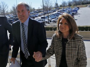 FILE - In this Feb. 16, 2017, file photo, Texas Attorney General Ken Paxton, left, arrives at the Collin County Courthouse with his wife Angela in McKinney, Texas. The wife of Texas Attorney General says a bill she filed that would change state securities law "literally has nothing to do" with her husband's criminal case on charges of defrauding investors. Republican state Sen. Angela Paxton, who was elected in November, said Tuesday, Feb. 19, 2019, that she didn't consult with her husband on the bill, which calls for the attorney general's office to create a framework that would let entrepreneurs test some financial products and services without a license.