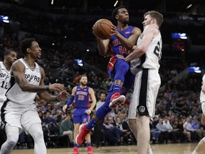 Detroit Pistons guard Ish Smith (14) crashes into San Antonio Spurs center Jakob Poeltl (25) as he drives with ball during the first half of an NBA basketball game in San Antonio, Wednesday, Feb. 27, 2019.