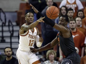 Texas guard Kerwin Roach II, left, passes the ball around Oklahoma State forward Cameron McGriff during the first half of an NCAA college basketball game, Saturday, Feb. 16, 2019, in Austin, Texas.