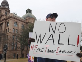 Jay Platt holds a sign during a protest in downtown Fort Worth, Texas, Monday, Feb. 18, 2019. People gathered on the Presidents Day holiday to protest President Donald Trump's recent national emergency declaration.