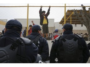 Central American immigrants hang around by the fence line of a shelter guarded by Mexican Federal police in riot gear in Piedras Negras, Mexico, Tuesday, Feb. 5, 2019. A caravan of about 1,600 Central American migrants camped Tuesday in the Mexican border city of Piedras Negras, just west of Eagle Pass, Texas. The governor of the northern state of Coahuila described the migrants as "asylum seekers," suggesting all had express intentions of surrendering to U.S. authorities.