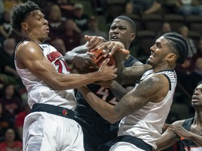 Louisville forward Dwayne Sutton, left, and Louisville center Malik Williams, right, battle Virginia Tech Hokies guard Ty Outlaw for the ball during the first half of an NCAA college basketball game Monday, Feb. 4, 2019, in Blacksburg, Va.