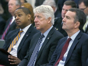 FILE - In this Dec. 18, 2017 file photo, from left, Lt. Governor-elect Justin Fairfax, Attorney General-elect Mark Herring and Governor-elect Ralph Northam listen as Virginia Governor Terry McAuliffe addresses a joint meeting of the House and Senate money committees at the Pocahontas Building in Richmond, Va.  With Virginia's top three elected officials engulfed in scandal, fellow Democrats were rendered practically speechless, uncertain of how to thread their way through the racial and sexual allegations and their tangled political implications.