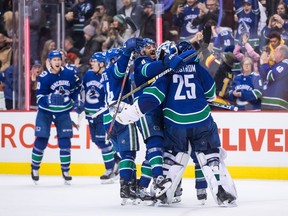 Vancouver Canucks goalie Jacob Markstrom (25), of Sweden, Chris Tanev (8) and Tyler Motte (64) celebrate their win following shootout NHL hockey action against the Calgary Flames, in Vancouver on Saturday, Feb. 9, 2019.