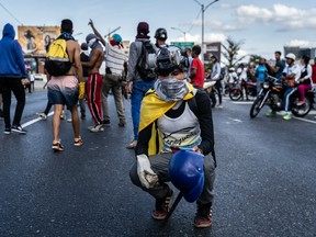 A demonstrator holding a rock kneels on the Francisco Fajardo Highway during a pro-opposition protest in Caracas, Venezuela, on Feb. 2, 2019.