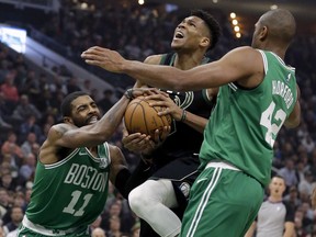 Boston Celtics' Kyrie Irving (11) forces a jump ball against Milwaukee Bucks' Giannis Antetokounmpo, center, during the first half of an NBA basketball game Thursday, Feb. 21, 2019, in Milwaukee.