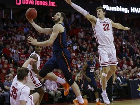 Illinois' Giorgi Bezhanishvili (15) fouls Wisconsin's Nate Reuvers (35) during the first half of an NCAA college basketball game Monday, Feb. 18, 2019, in Madison, Wis. At right is Wisconsin's Ethan Happ.