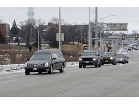 A hearse is seen in the procession as police vehicles leave Froedtert Hospital in Milwaukee, Wis., on Wednesday, Feb. 6, 2019, on their way to the Medical Examiners office with the hearse containing the body of a fallen Milwaukee Police officer. The Milwaukee Police Department is in mourning for the third time in less than a year after an officer was shot and killed Wednesday morning. The officer, whose name has not been released, was a member of the Tactical Enforcement Unit and was part of the team serving a search warrant at a house on the city's south side when he was shot with a rifle, according to three law enforcement sources.
