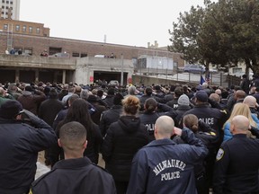 Hundreds of police officers fill in the back entrance to the Medical Examiner's office and salute while the casket is moved from the hearse in Milwaukee on Wednesday, Feb. 6, 2019. A 17-year police veteran was shot and killed as he served a warrant on Milwaukee's south side Wednesday, becoming the city's third officer to be killed in the line of duty in eight months, officials said. The 35-year-old officer's name has not been released.