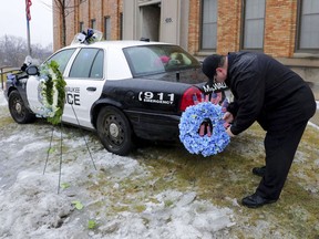 Timothy Nelson, of Oak Creek, Wis., places small flags in a bouquet near a squad car adorned with flowers as a memorial for fallen Milwaukee Police Officer Matthew Rittner at the Neighborhood Task Force police building in Milwaukee on Thursday, Feb. 7, 2019.  Police are collecting evidence at a Milwaukee home where a police officer was fatally shot while serving a warrant. Investigators say 35-year-old Officer Matthew Rittner was killed Wednesday as members of Milwaukee's Tactical Enforcement Unit served the warrant on someone suspected of illegally selling firearms and drugs.