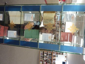 This Thursday Jan. 17, 2019 photo shows Ohio County Public Library staff member Erin Rothenbuehler places items in a display case to explain the historic significance of the five points on Wheeling's new official city flag, which she designed at the library in Wheeling W.Va.  The major exhibit coincides with Wheeling 250, a year-long celebration of the 250th anniversary of the city's founding.