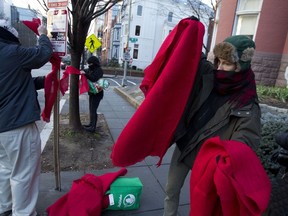 Demonstrators protest against the president of the Philippines and the bloodshed on his war on drugs by tying hundreds of strips of red cloth to the trees and signs outside of the Philippines Embassy in Washington, Wednesday, Feb. 13, 2019. In the nation's capital, it can be hard for protesters to stand out. Fifty people _ or even 500 _ holding signs and shouting hardly merits a second glance in this city of protests. That's why Washington activists have to get creative.
