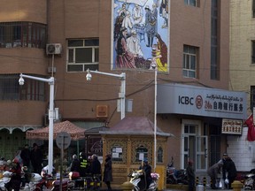 FILE - In this Nov. 5, 2017, file photo, residents pass by a security checkpoint and surveillance cameras mounted on a street in Kashgar in western China's Xinjiang region. The Chinese database Victor Gevers found online was not just a collection of old personal details. The discovery by Gevers, a Dutch cybersecurity researcher who revealed it on Twitter last week, has given a rare glimpse into China's extensive surveillance of Xinjiang, a remote region home to an ethnic minority population that is largely Muslim. The area has been blanketed with police checkpoints and security cameras that apparently are doing more than just recording what happens. The database Gevers found appears to have been recording people's movements tracked by facial recognition technology, he said, logging more than 6.7 million coordinates in a span of 24 hours.