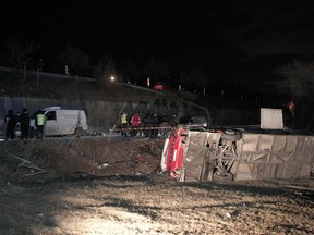 Police and investigators stand near the bus wreckage at the crash site at village of Laskarci, west of Skopje, North Macedonia, Wednesday, Feb. 13, 2019. Macedonia's health minister says some have died and many are injured in the bus crash, carrying workers on a highway west of the capital, Skopje.