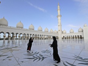 Two women take pictures outside the Grand Mosque of Sheikh Zayed, in Abu Dhabi, United Arab Emirates, Monday, Feb. 4, 2019. Pope Francis has arrived at the presidential palace to officially start his historic visit to the United Arab Emirates as canons boomed and a military aircraft flew over trailing the yellow and white smoke of the Holy See flag.