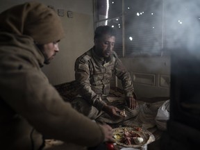 U.S.-backed Syrian Democratic Forces (SDF) fighters eat in a building as the fight against Islamic State militants continues in the village of Baghouz, Syria, Sunday, Feb. 17, 2019. Islamic State militants are preventing more than 1,000 civilians from leaving a tiny area still held by the extremist group in a village in eastern Syria, a spokesman for the U.S.-backed Syrian militia fighting the group said Sunday.