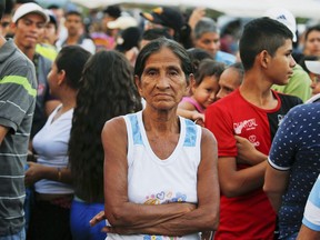 A woman poses for a photo as she lines up to receive bags with food subsidized by Venezuelan President Nicolas Maduro's government near the international bridge of Tienditas on the outskirts of Urena, Venezuela, Monday, Feb. 11, 2019, on the border with Colombia. Nearly three weeks after the Trump administration backed an all-out effort to force Maduro out, the embattled socialist leader is holding strong and defying predictions of an imminent demise.