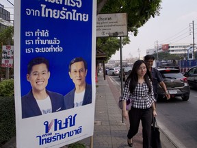 Pedestrians walk past an election poster promoting members of the Thai Raksa Chart political party in Bangkok, Thailand, Wednesday, Feb 13, 2019. The Thai Raksa Chart party, which took the unprecedented and ultimately unsuccessful step of nominating a member of the royal family as its candidate for prime minister, is fighting for its political life as the Election Commission says it has recommended that it be dissolved.