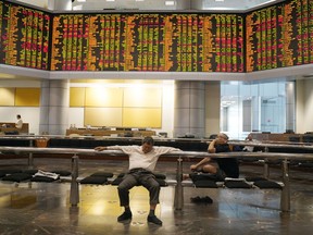 Visitors sit in front of private stock trading boards at a private stock market gallery in Kuala Lumpur, Malaysia, Friday, Feb. 22, 2019. Asian shares were mostly lower Friday after a slide on Wall Street as investors nervously watched the U.S.-China trade talks in Washington.