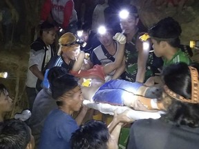 In this undated photo released by Indonesian Search And Rescue Agency (BASARNAS) rescuers evacuate a survivor from a collapsed gold mine in Bolaang Mongondow, North Sulawesi, Indonesia. The collapse of an unlicensed gold mine in Indonesia's North Sulawesi province has buried dozens of people, a disaster official said Wednesday, Feb. 27, 2019, as emergency personnel used their bare hands and farm tools in a desperate attempt to reach victims calling for help from beneath the rubble. (BASARNAS via AP)