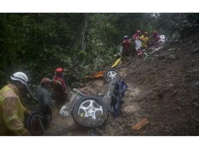 Firefighters look for victims after a mudslide on the outskirts of El Choro, Bolivia, Saturday, Feb. 2, 2019. According to police, at least five people died and others were injured after vehicles were dragged Saturday by a mudslide on a mountainous road in the north of La Paz.