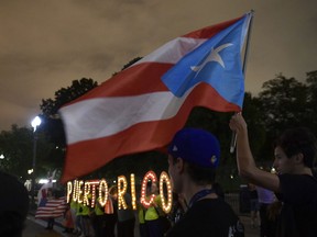 FILE - In this Sept. 20, 2018 file photo, people gather outside the White House in Washington, during a vigil commemorating the one-year anniversary of Hurricane Maria hitting Puerto Rico. A federal bankruptcy judge on Monday, Feb. 4, 2019 approved a major debt restructuring plan for Puerto Rico in the first deal of its kind for the U.S. territory since the government declared nearly three years ago that it was unable to pay its public debt.