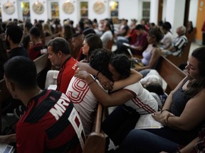 Two young women, wearing Flamengo soccer kits, embrace as they attend a memorial Mass for the victims of a fire at a Brazilian soccer academy, in Rio de Janeiro, Brazil, Friday, Feb. 8, 2019. A fire early Friday swept through the sleeping quarters of an academy for Brazil's popular professional soccer club Flamengo, killing 10 people and injuring three, most likely teenage players, authorities said.