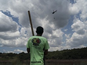 Fernando Nunes watches a helicopter carry a body away from the mud after a Vale dam collapse in Brumadinho, Brazil, Wednesday, Jan. 30, 2019, while his brother Peterson, a Vale employee, remains missing. Two days after this photo was taken, his brother's body was found, recovered and identified by their mother.