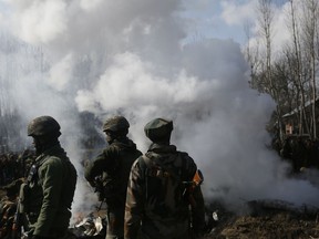 Indian soldiers stand near the wreckage of an Indian helicopter after it crashed on the outskirts of Srinagar, in Indian-controlled Kashmir, on Feb. 27, 2019. The crash killed six Indian air force officials and a civilian on the ground.