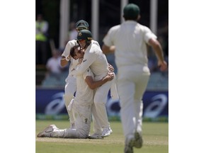Australia's Pat Cummins, left, celebrates with teammate Marcus Harris after Cummins caught and bowled Sri Lanka's Lahiru Thirimanne on day 4 of their cricket test match in Canberra, Monday, Feb. 4, 2019.