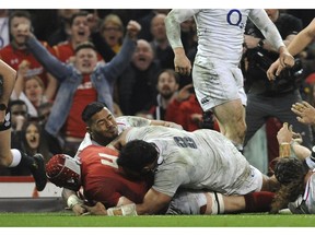 Wales Cory Hill scores a try in the tackle of England's Billy Vunipola and Manu Tuilagi during the Six Nations rugby union international between Wales and England at the Principality Stadium in Cardiff, Wales, Saturday, Feb. 23, 2019.