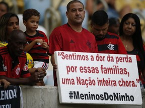 A fan holds a sign with a message that reads in Portuguese: "We feel the pain for the families, an entire nation weeps," as he waits for the start of a homage for the 10 teenage players killed by a fire at the Flamengo training center last Friday, at the Maracana Stadium, in Rio de Janeiro, Brazil, Thursday, Feb. 14, 2019, ahead of a soccer match between Flamengo and Fluminense.